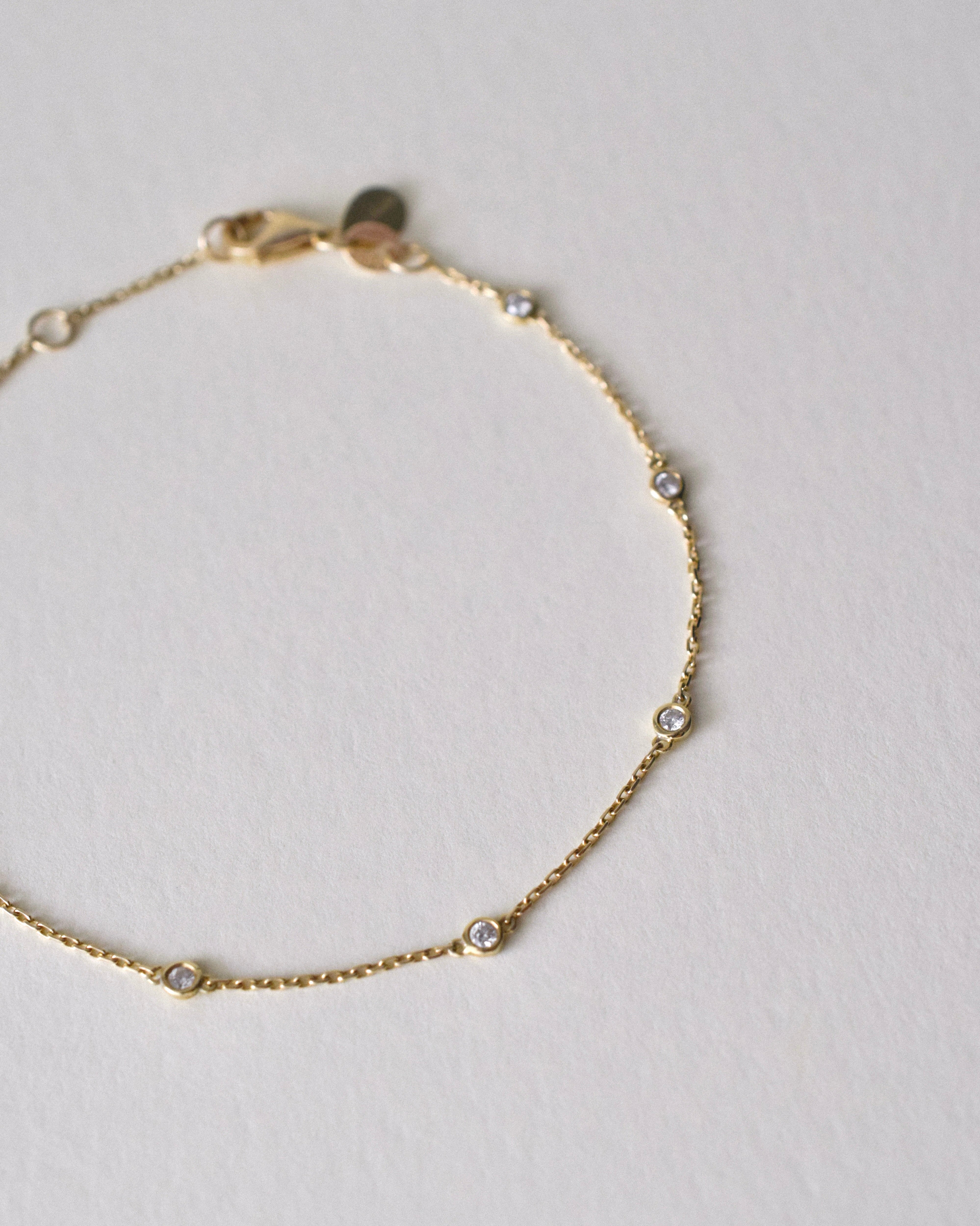 Gold bracelet with small diamonds on a light gray background
