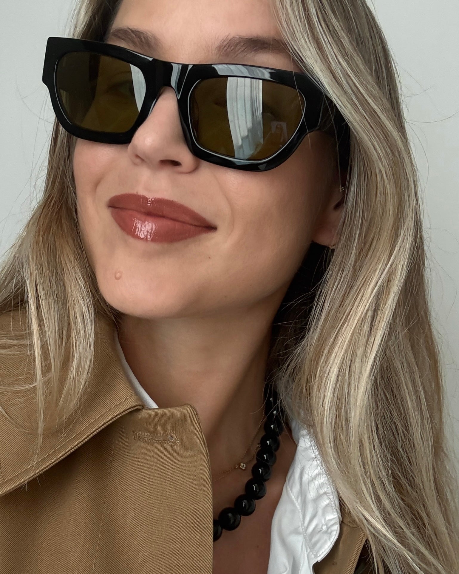 Woman wearing a black beaded onyx necklace and sunglasses with a neutral background