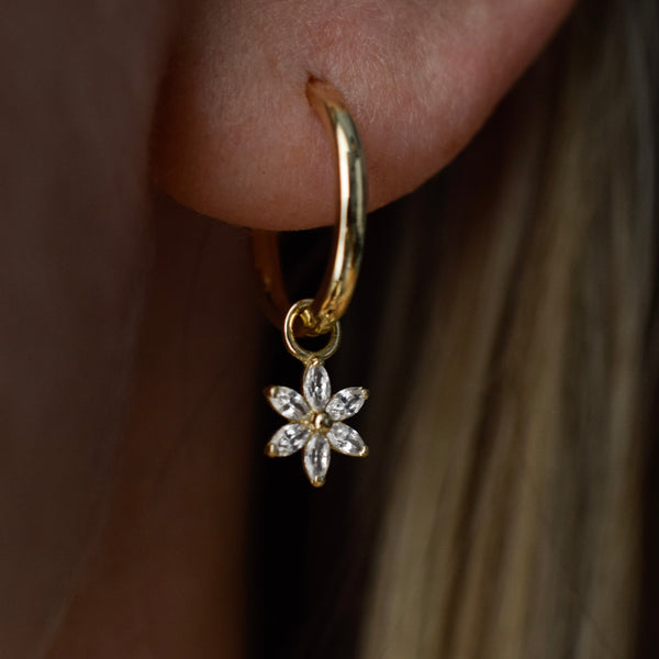 Flower Charm with cubic zirconia stones dangling on a 14k solid gold hoop earring