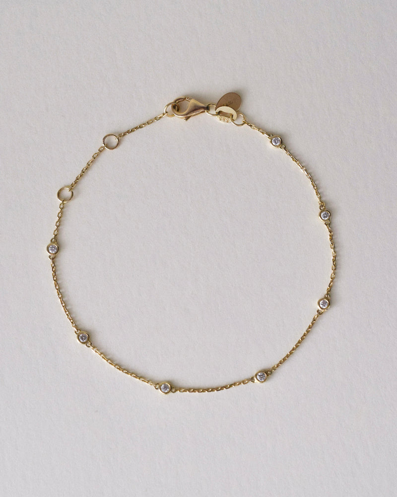 Gold bracelet with 7 diamonds by the yard on a light gray background