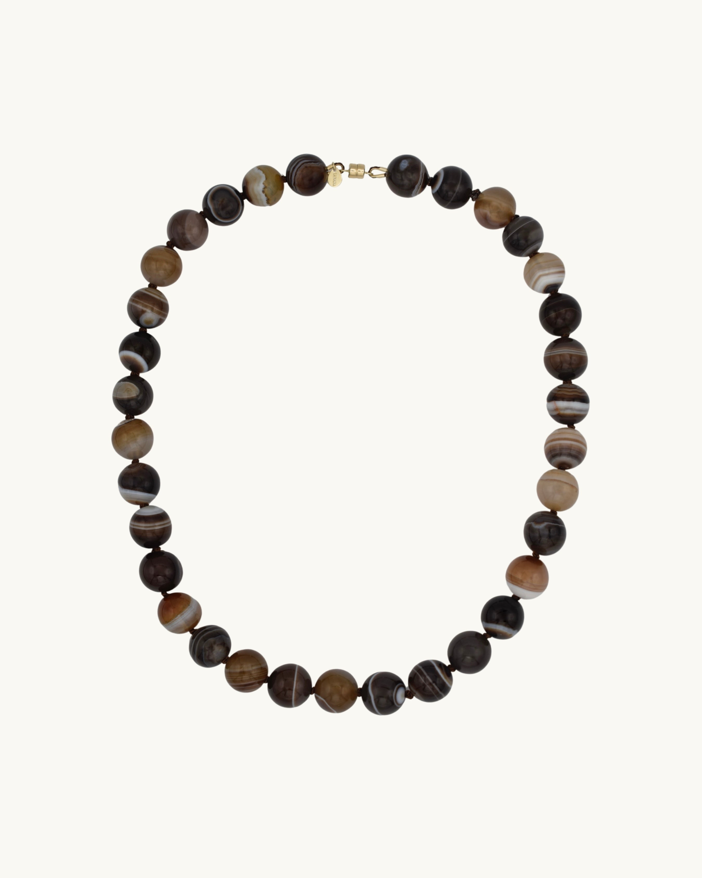 Necklace with round grey-brown striped beads on a white background with gold magnetic clasp