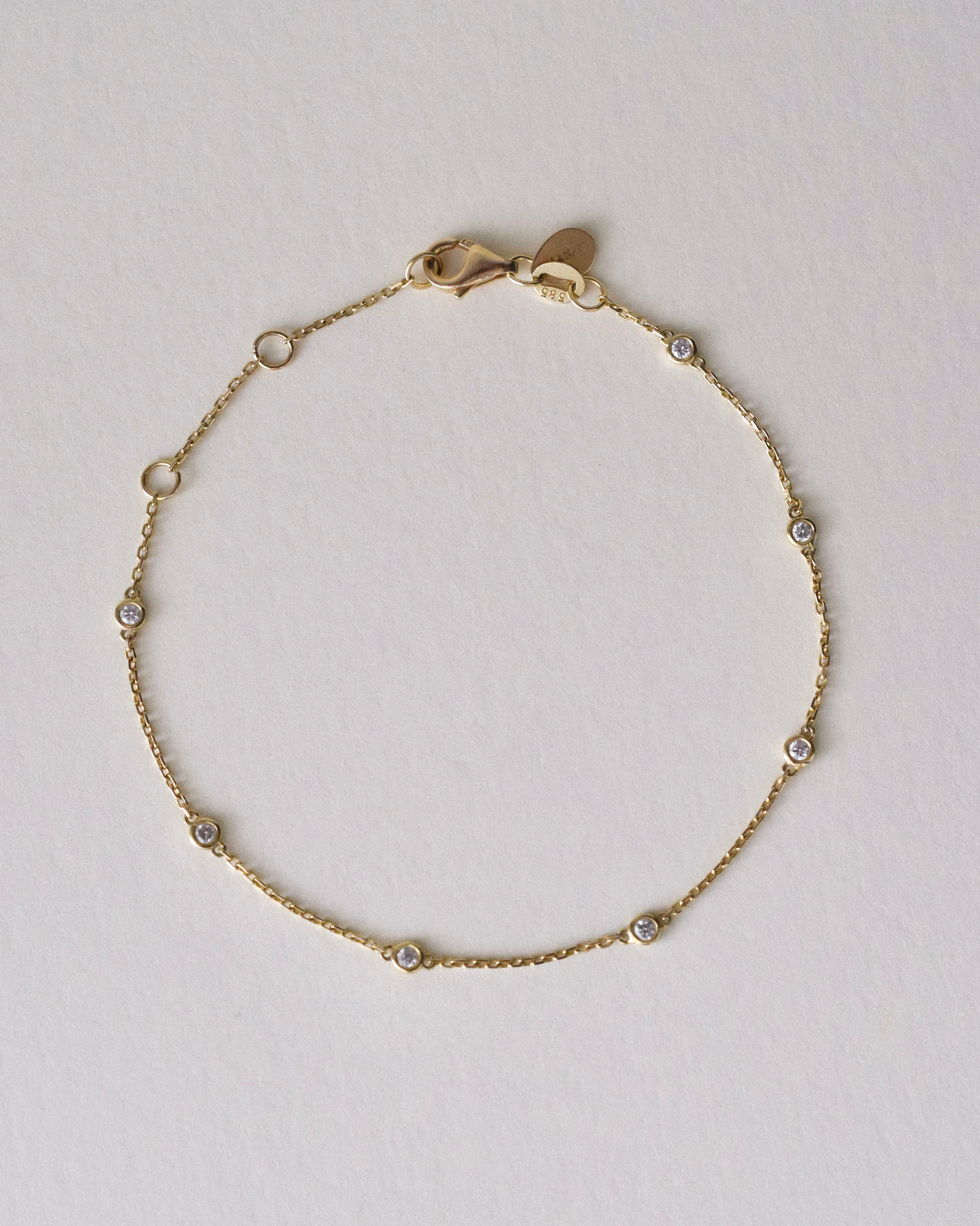 Gold bracelet with 7 diamonds by the yard on a light gray background